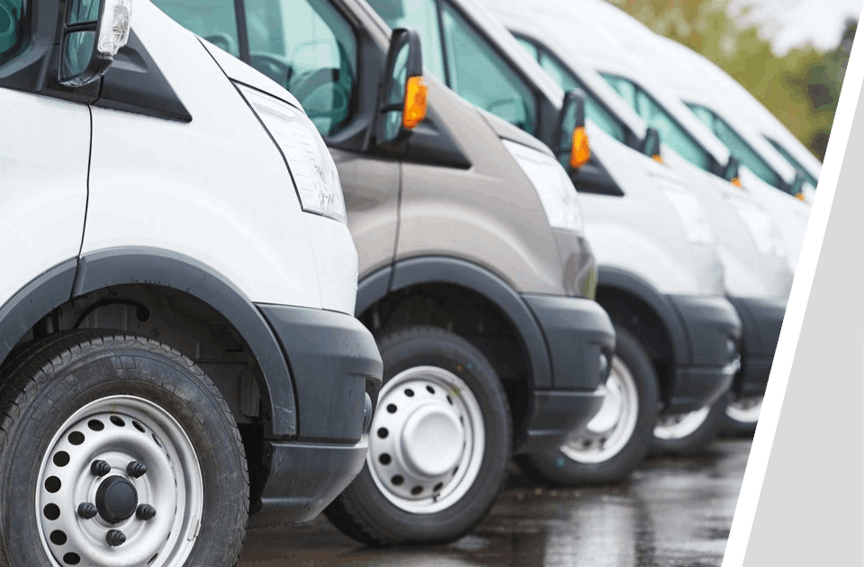 A row of white vans parked in the rain.