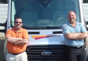 Two men standing in front of a truck.